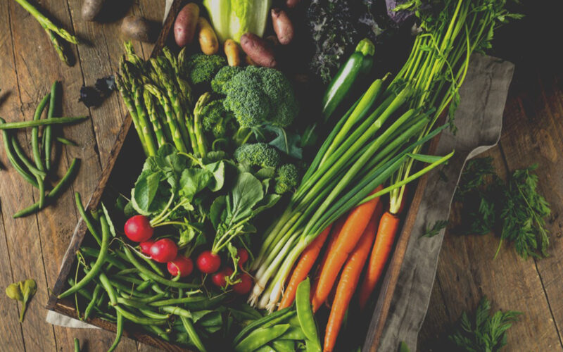 spring vegetables in basket on a wood table